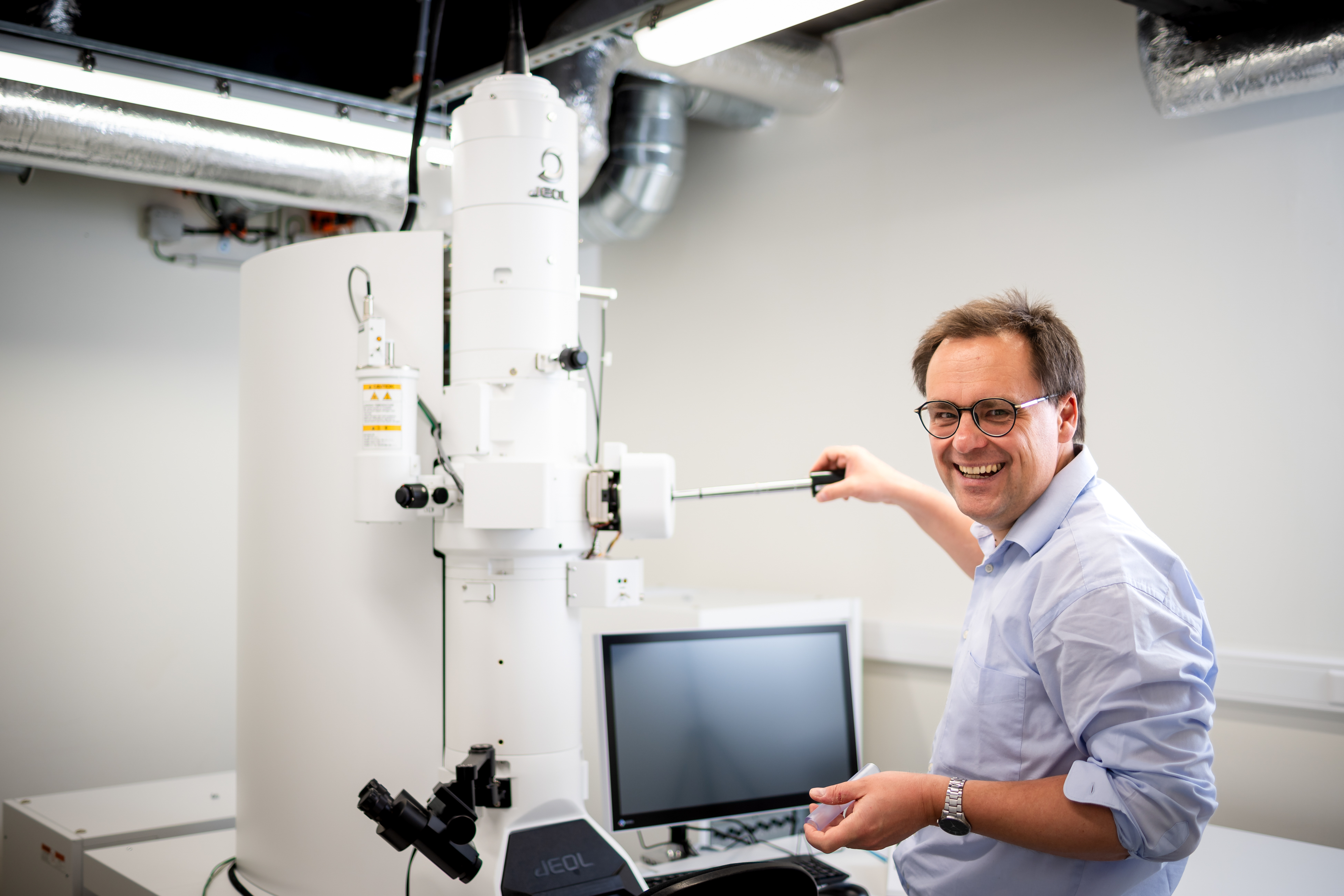 Onderzoeker BCEM staat bij reuzenmicroscoop