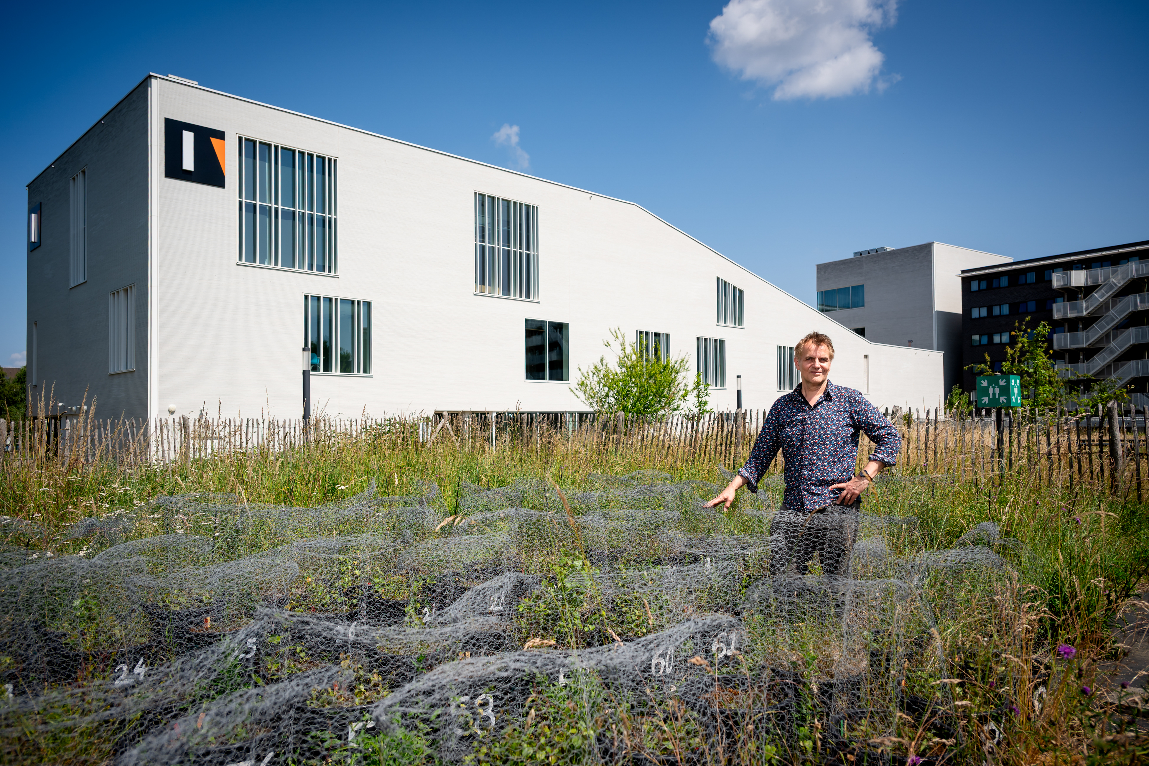 Onderzoeker met planten buiten aan gebouw I